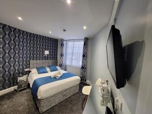 una camera da letto con un letto con cuscini blu e una TV di George Hotel a Londra