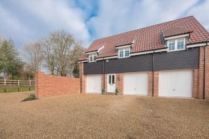 a house with two garage doors and a brick wall at 10 Acorn Close Aldringham in Leiston