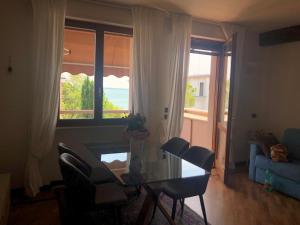 a living room with a glass table and chairs and a window at Appartamento direttamente a lago in Sirmione