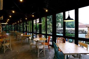 a restaurant with tables and chairs and large windows at Namin Dago Hotel in Bandung