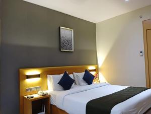 a hotel room with a large bed with blue pillows at Hotel Suba Elite Vadodara in Vadodara