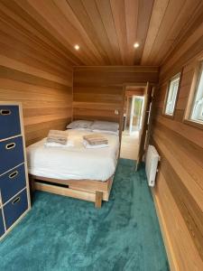 a small bedroom with a bed in a wooden cabin at East Learmouth Lakeside Lodges - Larch Lodge in Cornhill-on-tweed