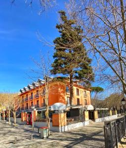 um edifício laranja com uma árvore em frente em Hospedium Hotel Los Lanceros em San Lorenzo de El Escorial