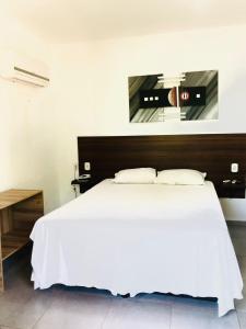 a bedroom with a white bed and a mirror at Princesinha do Sul in Ilhéus