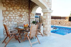 eine Terrasse mit einem Tisch, Stühlen und einem Pool in der Unterkunft Deluxe Villa LaCasa 2 with Private Pool in Roumelí
