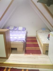 a attic bedroom with two beds and a rug at Apartmani Jovičić in Užice