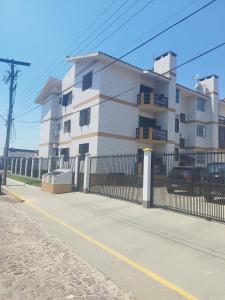 a building on the side of a street with a fence at Apartamento no condomínio Mediterranée- 3 quadras do mar- 1 dormitório em Capão Novo in Capão da Canoa