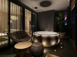 THE skM TOKYO HOTEL & DINING في طوكيو: شرفة مع حوض وكرسي ومقعد