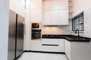 a kitchen with white cabinets and a stainless steel refrigerator at Palm Spring Luxury Apartment in Port Harcourt