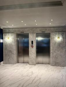 2 puertas de ascensor en un vestíbulo con suelo de mármol en Apartamento novo Gran Safira, en Itapema