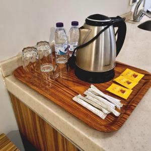 a tea kettle and glasses on a wooden cutting board at SPAR Furnished Hotel in Al Hofuf