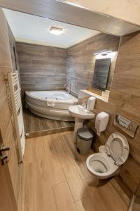 a bathroom with a tub and a toilet and a sink at Pensiunea Aria Paltinis in Păltiniş