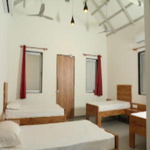 2 camas en una habitación con cortinas rojas en Nature fun resort en Pune