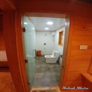 baño con aseo y puerta de cristal en Nature fun resort en Pune