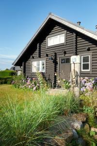 ein schwarzes Haus mit einer Tür und ein paar Blumen in der Unterkunft HAUS ZWEINEUN in Brodersby