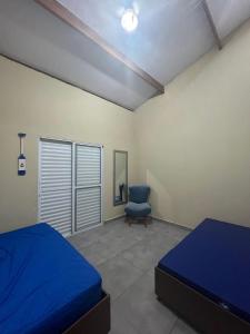 a bedroom with two beds and a blue chair at Casa para aluguel de temporada em Caraguatatuba, ao lado de São Sebastião in Caraguatatuba