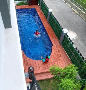 two children playing in a large swimming pool at A home with private pool, Kebun Kecil in Tangga Batu