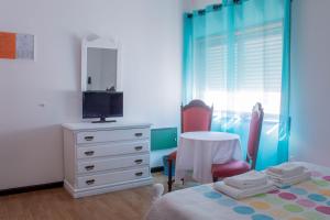 a bedroom with a bed and a dresser with a tv at Residencial Princesa do Ave in Vila do Conde