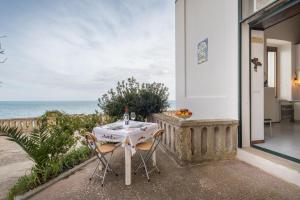 Casa sul Mare - Tricase في مارينا بورتو: طاولة وكراسي على شرفة مطلة على المحيط