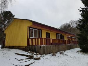 a yellow house with a fence in the snow at Tammispea puhkeküla 