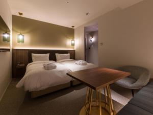 a bedroom with a bed and a table and a chair at THE skM TOKYO HOTEL & DINING in Tokyo