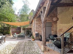 eine Terrasse mit Stühlen und Tischen sowie ein Backsteingebäude in der Unterkunft Le Clos de Miribel in Givry