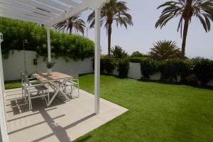 Un patio con una mesa y sillas bajo una pérgola blanca. en Bungalow con jardín en Pasito PM40, en Pasito Blanco