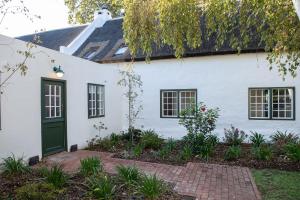 a white house with a green door at Taaibosch Collection in Stellenbosch