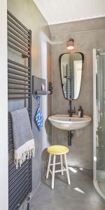 ein Badezimmer mit einem Waschbecken, einem Spiegel und einem Stuhl in der Unterkunft HAUS ZWEINEUN in Brodersby