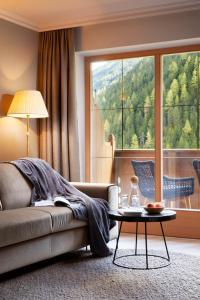 a living room with a couch and a table and a large window at Adler Inn Tyrol Mountain Resort SUPERIOR in Tux