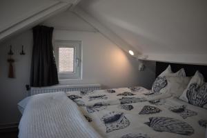 a bedroom with a bed with a white comforter and a window at ZeeBedStay in Noordwijk aan Zee