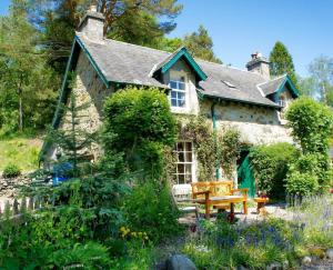 mały kamienny dom z ławką w ogrodzie w obiekcie Granite Cottage w mieście Bridge of Cally