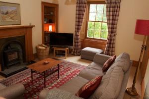 salon z kanapą i kominkiem w obiekcie Granite Cottage w mieście Bridge of Cally