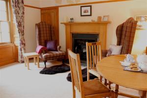 a living room with a table and chairs and a fireplace at Granite Cottage in Bridge of Cally