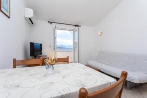 a room with a table and a bed and a television at Apartments Crnekovic I Zarok in Ba&scaron;ka