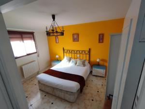 a bedroom with a bed and a yellow wall at El Cortijo del Piron in Losana de Pirón