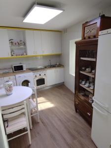 a kitchen with white cabinets and a table and a refrigerator at El Cortijo del Piron in Losana de Pirón