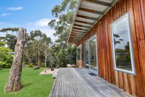 a wooden deck on the side of a house with a tree at Flounder in Lake Tyers