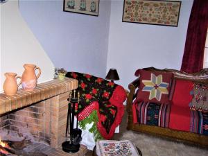 a living room with a fireplace with a christmas blanket on a chair at Kastorio-Villy's Guest House in Kastórion