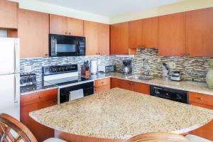 cocina con armarios de madera y encimera de granito en Coral Gardens on Grace Bay, en Grace Bay