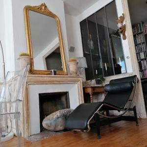 a chair in front of a fireplace with a mirror at The Appart 90m2 au coeur de la vieille ville in La Rochelle