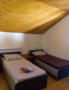 two beds in a room with a wooden ceiling at Vila Natalija in Podgorica