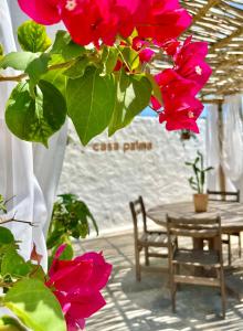 a table and a bunch of red flowers on a porch at Casa Palma in São Miguel do Gostoso