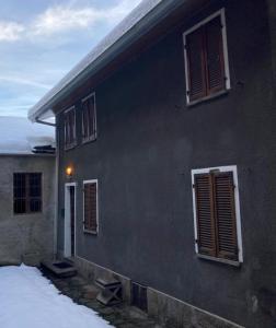 Casa Milietta في Gravere: مبنى أسود بنوافذ وثلج أمامه