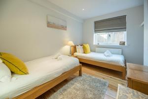 a bedroom with two beds and a window at The White House Southwold in Southwold