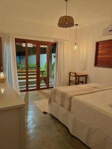 a bedroom with a bed and a table and a window at Casa Palma in São Miguel do Gostoso