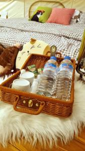 Una cesta llena de botellas de agua y platos en una cama en Cat A Camp - Khao Yai, 