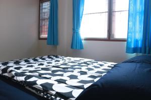 a bed in a bedroom with blue curtains and a window at ChillHouse24 @ DonMueang in Ban Don Muang