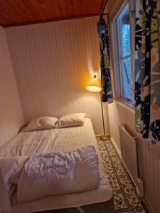 a bedroom with a bed and a lamp and a window at Utsikt mot viken in Undenäs