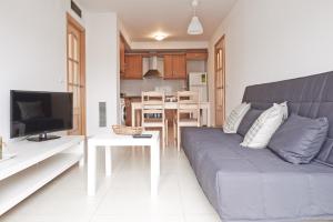 uma sala de estar com um sofá azul e uma cozinha em Torredembarra em Torredembarra